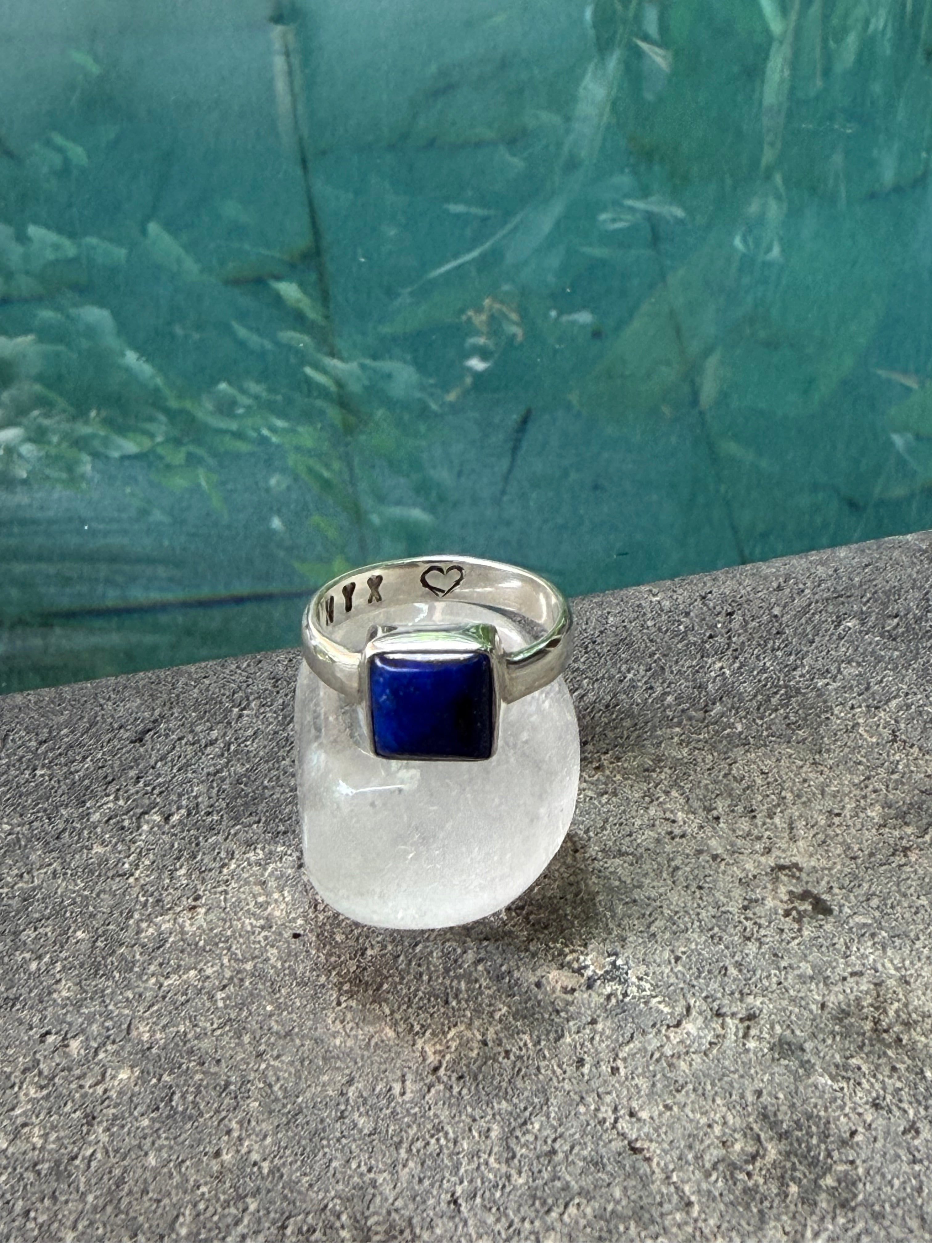 Silver ring with a blue gemstone on a concrete surface