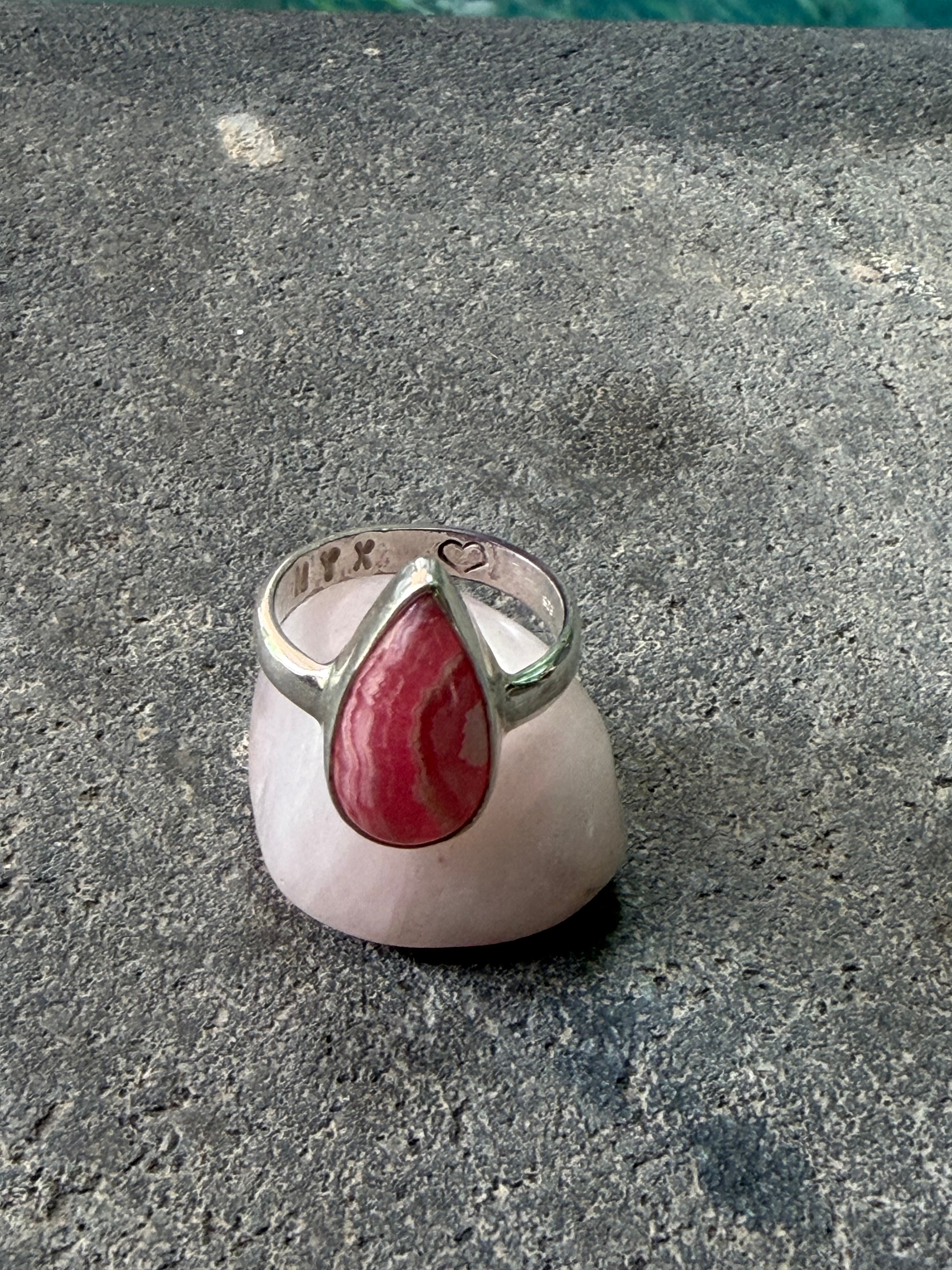 Silver ring with a red stone on a gray concrete surface