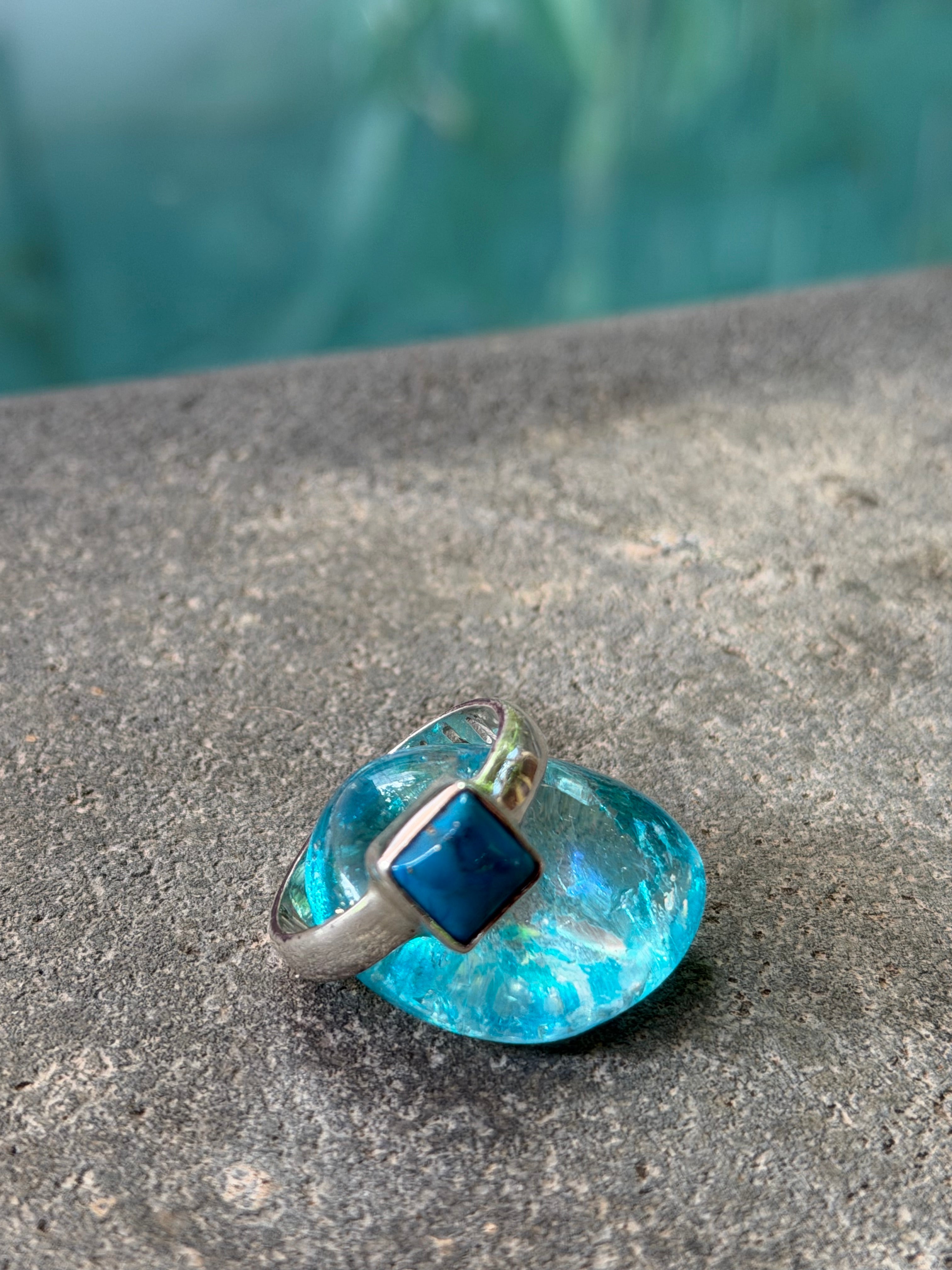 Blue glass knob on a stone surface with blurred water background